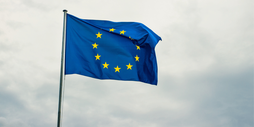 EU flag on mast with cloudy sky in background