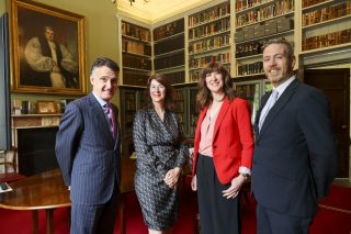 two men and two women in front of book shelves