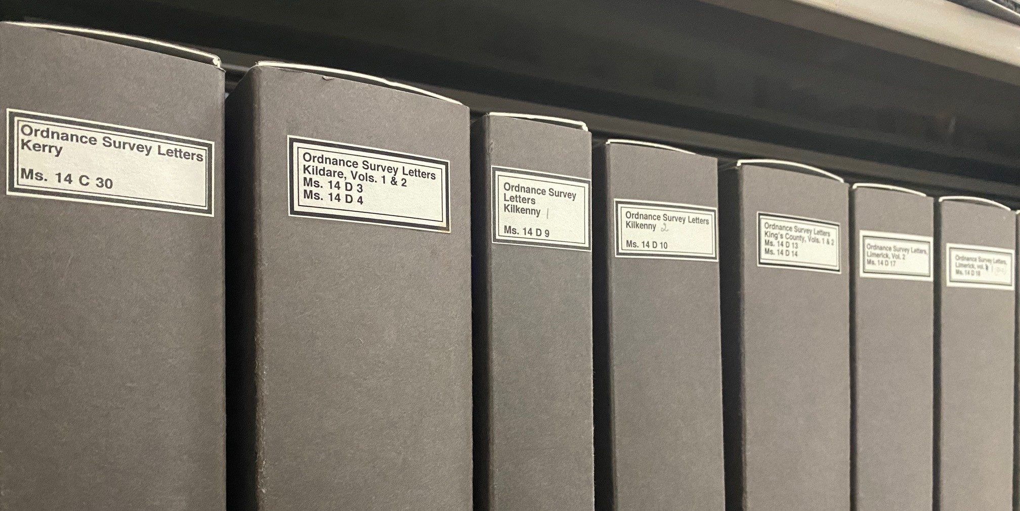 Grey archival boxes on a library shelf labelled as Ordnance Survey Letters with the relevant county.