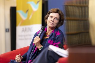 Woman sitting in a red chair holding a mic