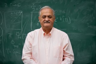 Photograph of Samson Shatashvili in front of a blackboard