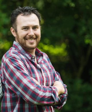 man in a checkered shirt with arms folded