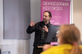 Conor Mulhern presents to a captivated audience, sharing knowledge and engaging with the listeners in a professional setting.