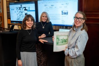 Noelia Romero, Rachel Murphy and Lisa Griffith with print and digital material of IHTA Cork with 2 screens in the background