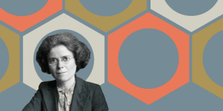 Kathleen Lonsdale in a suit and glasses seated before a geometric hexagon pattern backdrop.